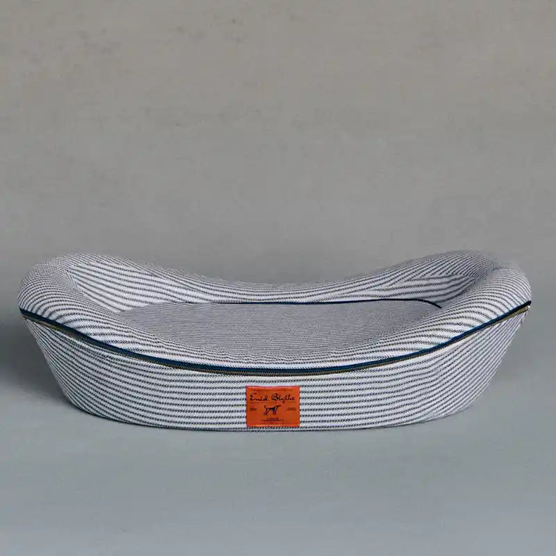Navy and white striped pet bed with brand label on a grey background