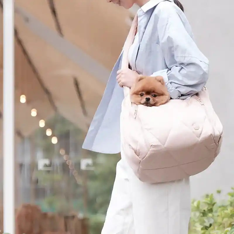 Woman wearing crossbody cloud pet carrier with a pomeranian's head sticking out of bag