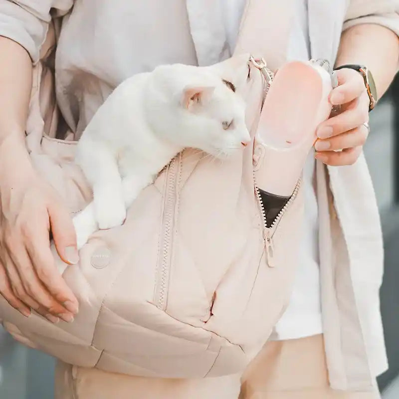 White cat in latte cloud carrier and water bottle sticking out of secret pocket