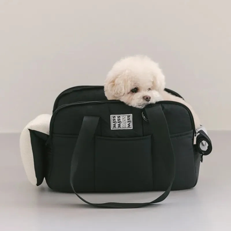 White fluffy dog peeking out of a black pet carrier bag