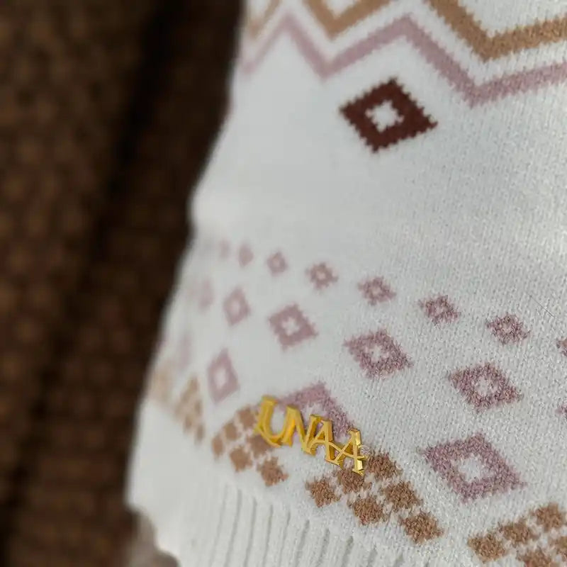 Close-up of cream fair isle sweater with LUNAA logo in gold