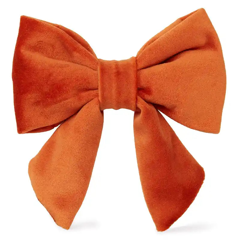 Front view of an orange velvet bow.