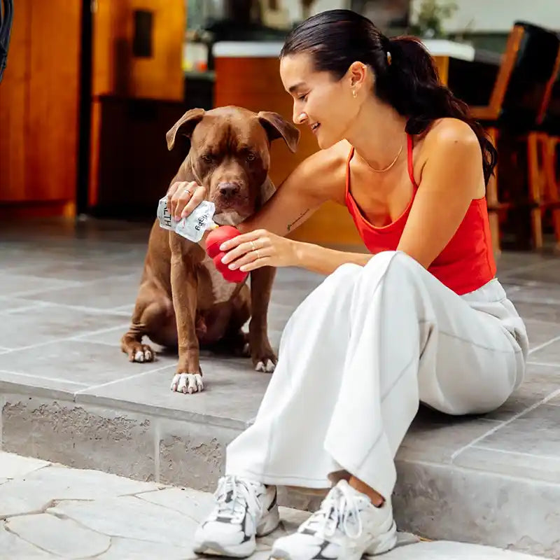 Woman squeezing rigby targeted support supplement into a red kong