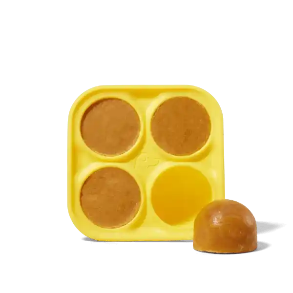 Yellow silicone mold with 4 frozen treats - 3 inside the cavities and 1 popped out to show dome shape