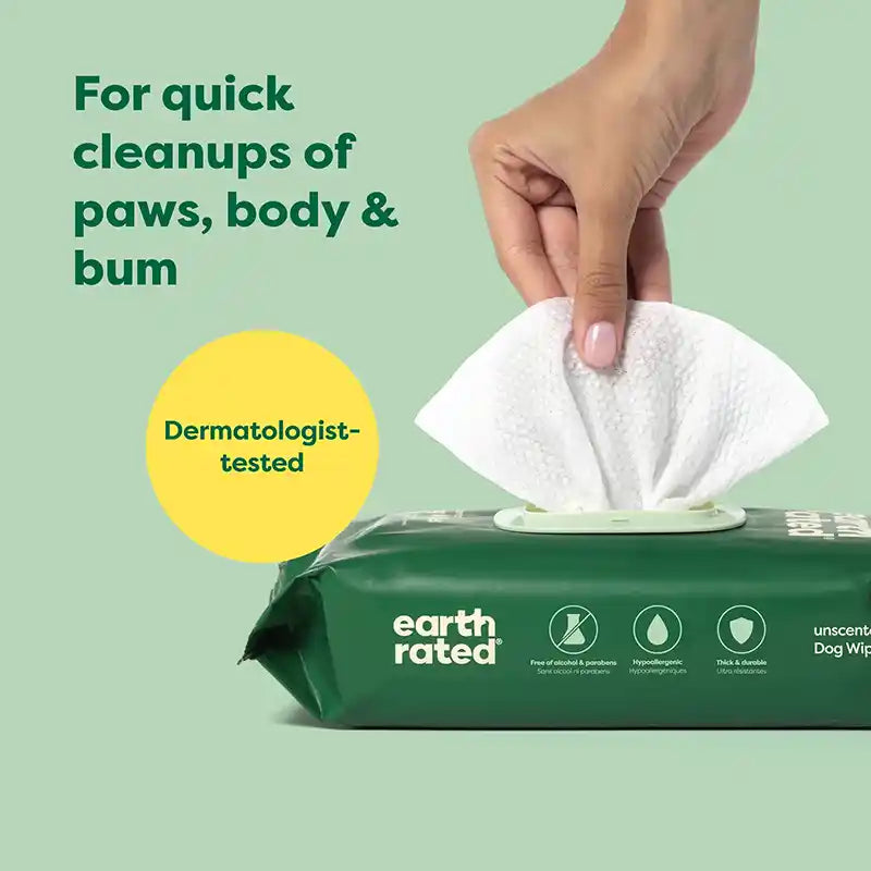 A hand pulling a wipe out of a green pack of Earth Rated dog wipes.