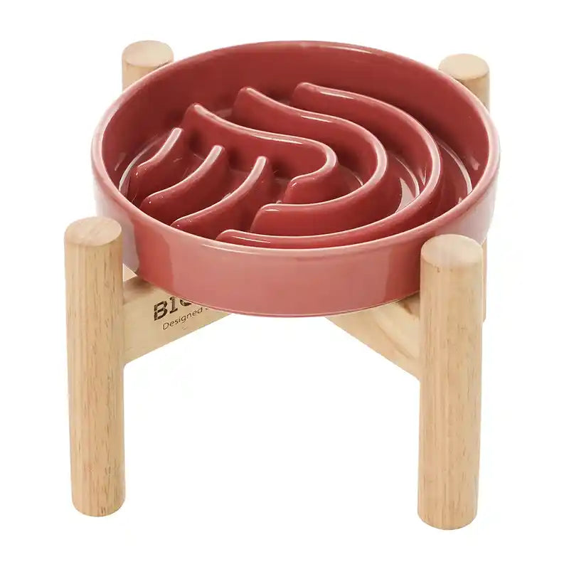 Pink pet slow feeder with wooden stand on a white background
