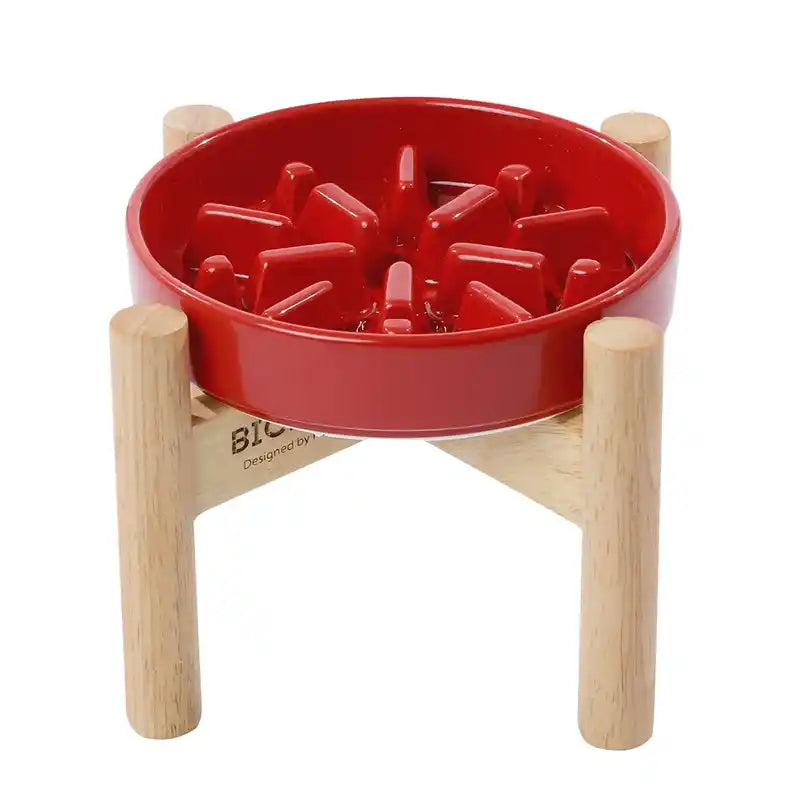 Red slow feeder pet bowl with wooden stand on a white background